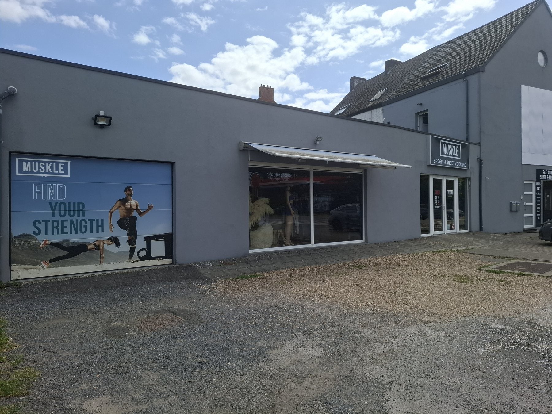 Breed aanzicht van MUSKLE Bonheiden met FIND YOUR STRENGTH-mural en ingang