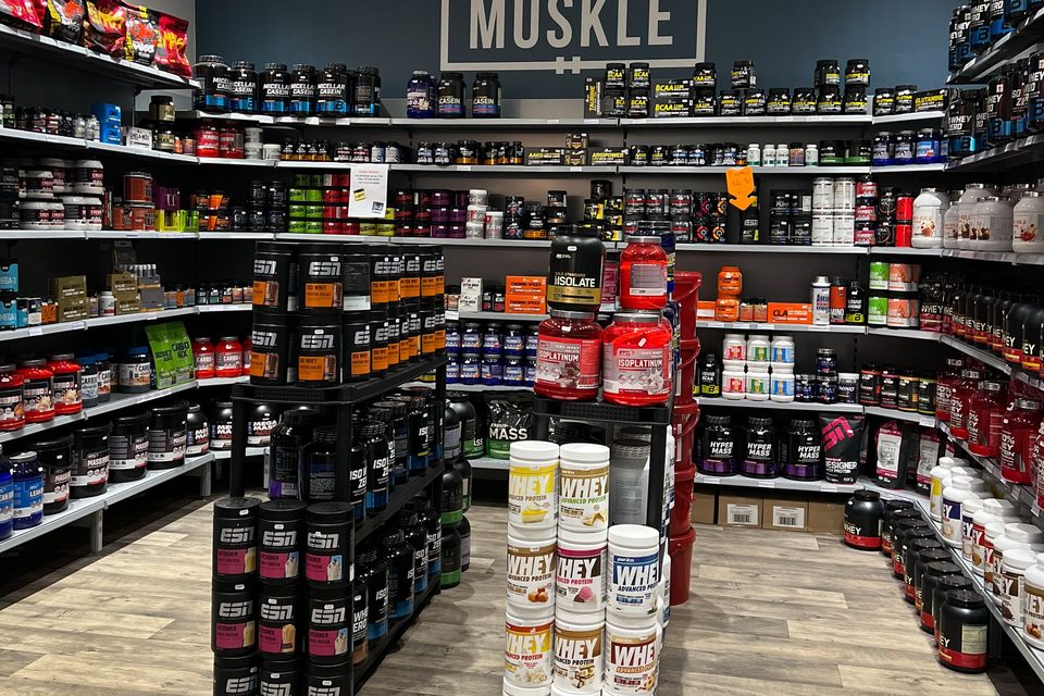 Interieur van de MUSKLE winkel in Antwerpen met productstellingen en MUSKLE logo