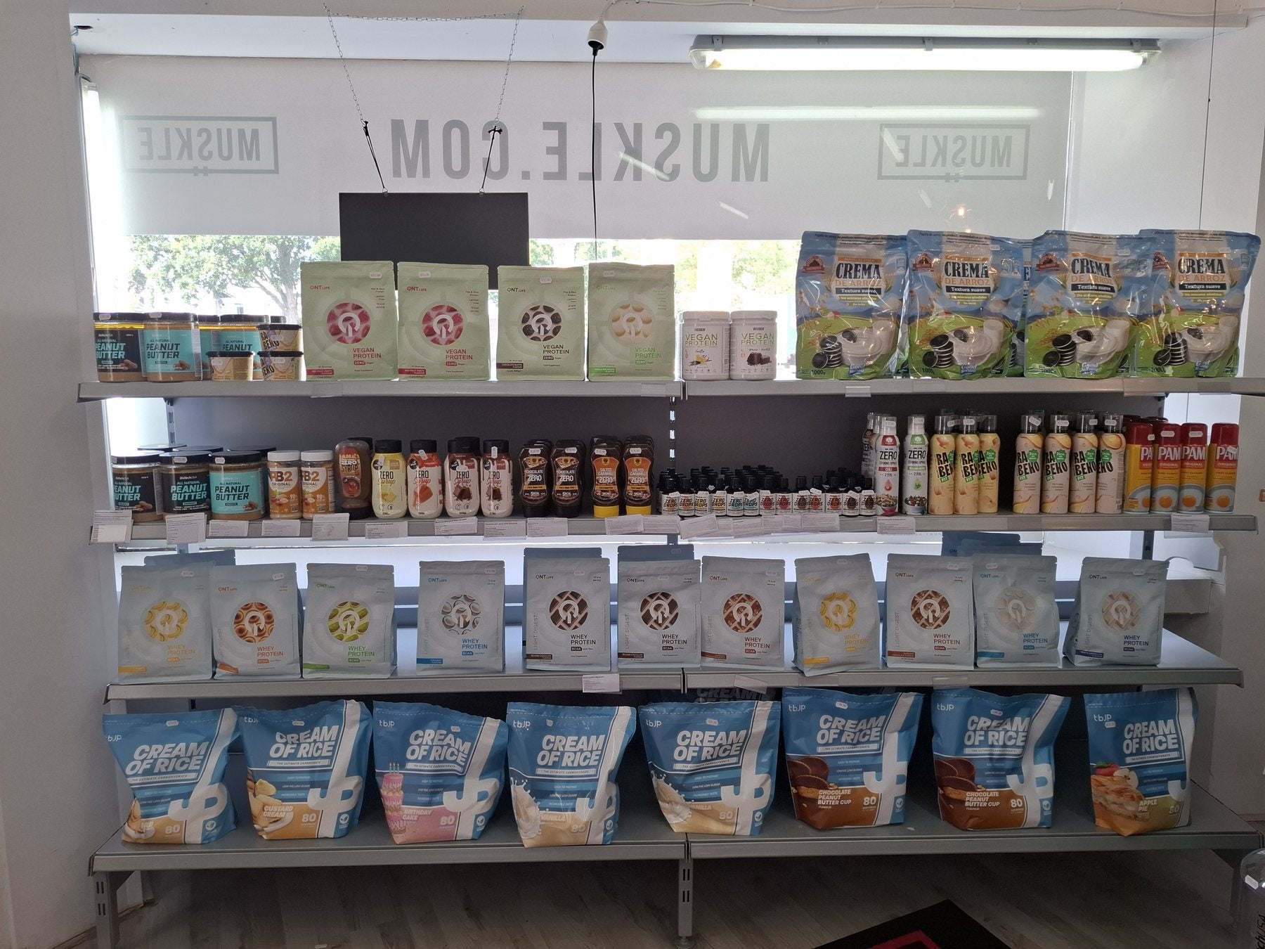 Rekken met whey, cream of rice en voeding bij het raam in MUSKLE Roosendaal
